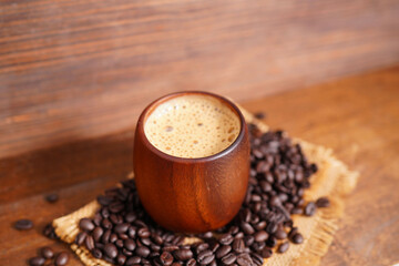 Hot coffee, cappuccino in a wooden cup and roasted coffee beans.