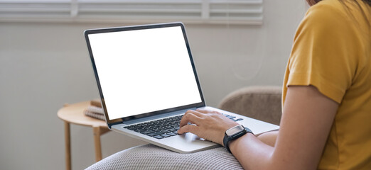 Young woman using laptop screen blank, mockup lying on the sofa at home