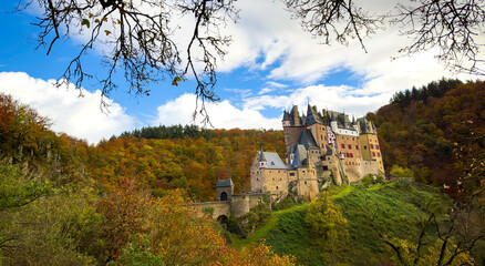 Autumn trees scene with Eltz Castle or Burg Eltz. Medieval castle on the hills above the Moselle...