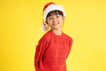 Image of an Asian girl wearing a Christmas sweater and hat posing on a yellow background
