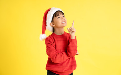 Image of an Asian girl wearing a Christmas sweater and hat posing on a yellow background
