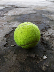 Close-up of a tennis ball on the broken floor. 