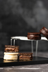 Alfajores de chocolate negro y blanco rellenos de dulce de leche sobre fondo oscuro.