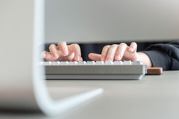 Manos de mujer tipeando con un teclado gris frente al ordenador. - obrazy, fototapety, plakaty