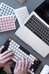 Mano humana usando un teclado blanco, negro y naranja.