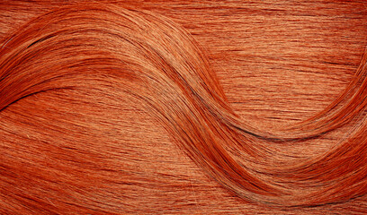 Naklejka premium Red hair close-up as a background. Women's long orange hair. Beautifully styled wavy shiny curls. Hair coloring bright shades. Hairdressing procedures, extension.