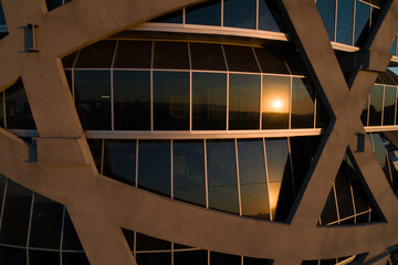 The sun sets in the reflection of a modern office building.