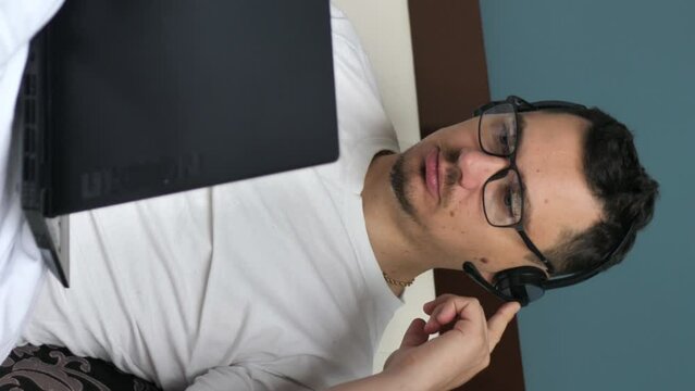 Young male teacher talking on video webinar using laptop. businessman at interview talking to team online. Remote online work concept. vertical screen