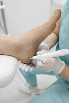 A female podologist does a hardware pedicure. Grinding the heel with a cutter close-up