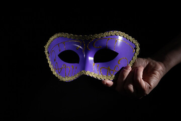 Carnival mask in hand, a vintage and theatrical piece for a circus party, black background