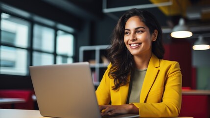 Woman smiling in office using laptop.