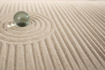 Miniature sand zen garden with a glass sphere and geometric dunes, abstract texture backdrop