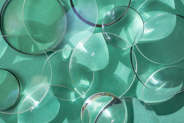 Clear glass round magnifying lenses on turquoise color paper , with light reflections and shadows,...