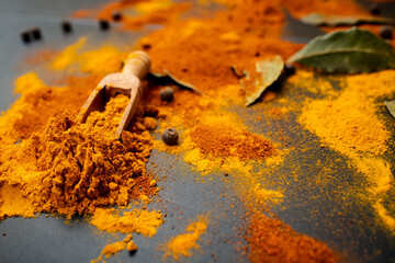 Scattered spices and bay leaves on black background, soft focus close up