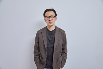 Handsome Asian businessman in suit with eyeglass smile and look at camera on grey background.