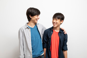 Caucasian and Asian teen boys wear shirt and stand on white background. Concept of mix raced.