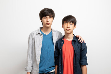 Caucasian and Asian teen boys wear shirt and stand on white background. Concept of mix raced.