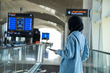 Young arab female holding her passport at the airport ready for new adventure with airplane in the...