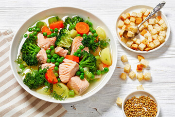 salmon, veggies and green herbs soup in bowl