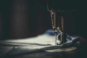 Fotobehang Vintage sewing machine, man sews on a vintage sewing machine, retro sewing machine © Anton