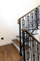 Interior of residential house or hotel. Contemporary wooden stairs with forged rails.