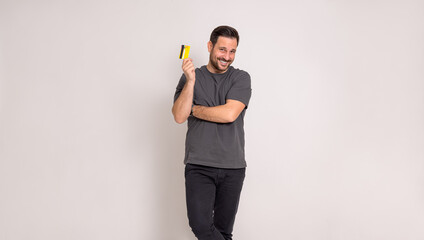 Positive young businessman smiling and showing credit card while standing on white background