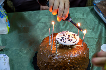 A hand lights the birthday candles on the cake for the celebration