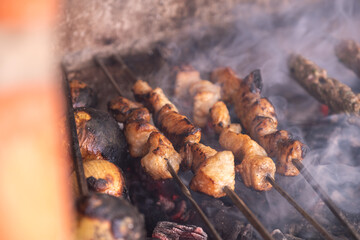 Roasted chickens on spit grilled over fire flame..