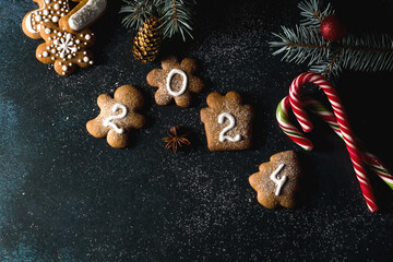 Gingerbread cookies of the form of numbers and 2024. Christmas composition with gingerbread on dark background. Copy space. Flat lay - obrazy, fototapety, plakaty