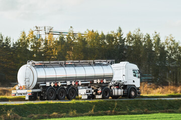Fototapeta na wymiar Liquid Fuel and Oil Cargo Semi Truck on the Highway. Compressed Gas Carrier Truck in the Evening Light. Hauling Petroleum Products. Oil Cargo Truck Hauling Petroleum Products.