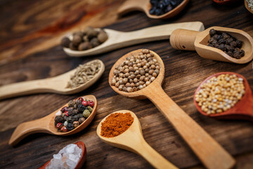 Many different spices in wooden spoons on a wooden background, background with spices, spices in spoons