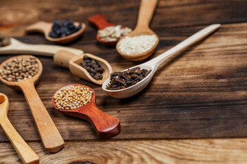 Many different spices in wooden spoons on a wooden background, background with spices, spices in spoons