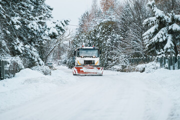 A snowplow truck clears the highway from snow during a winter storm. Snow blowing out of the plow...