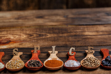 Many different spices in wooden spoons on a wooden background, background with spices, spices in...