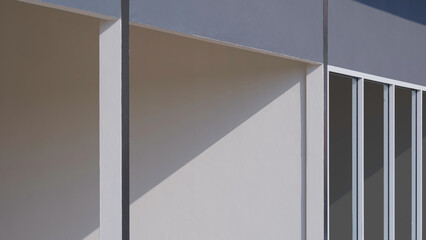 Light and shadow on surface of concrete and glass wall of beige rental shophouse in perspective...