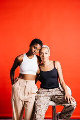 Naklejka premium Portrait of a young female couple in front of a red background at studio. Two women together at studio.