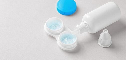 Contact lenses in container with solution bottle o on beige background