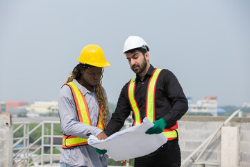 Foreman builder male and female at construction site. Group of foreman construction working at construction site, wearing safety uniform, helmet and holding blueprint structure