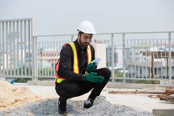Foreman builder male working and inspecting quality of materials at construction site, wearing...