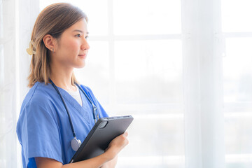 Asian Female medical assistant with smart tablet in white background. Portrait of mature female nurse working in hospital. Woman healthcare worker. Portrait of a good looking young nurse.