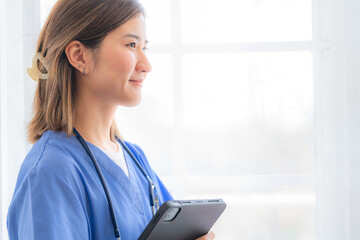 Asian Female medical assistant with smart tablet in white background. Portrait of mature female nurse working in hospital. Woman healthcare worker. Portrait of a good looking young nurse.