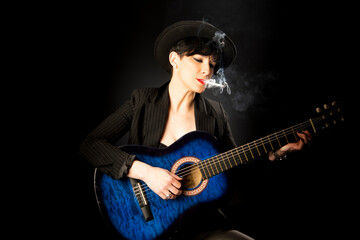 Fototapeta na wymiar Young beautiful woman in black with a cigarette and an acoustic blue guitar
