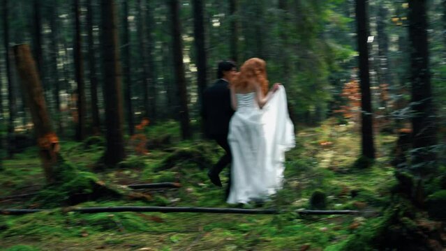 A bride with red hair poses with the groom in a pine forest. Fairytale wedding couple. Wedding concept