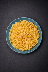 Raw whole grain wheat pasta with salt and spices in a ceramic plate