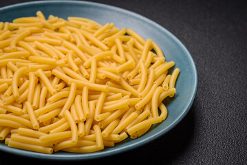 Raw whole grain wheat pasta with salt and spices in a ceramic plate