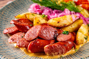 Potatoes with sausages and vegetables, cut into slices and fried in oil on plate
