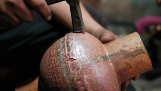 Master, tinsmith, making the jug from copper. Hand-minting copper. Ancient art of making crockery. Handicraft. Central Asia, Bukhara, Uzbekistan