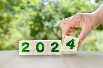 new year 2024 concept. Man holds onto 2024 cube on wood floor. Merry Christmas and Happy New Year,...