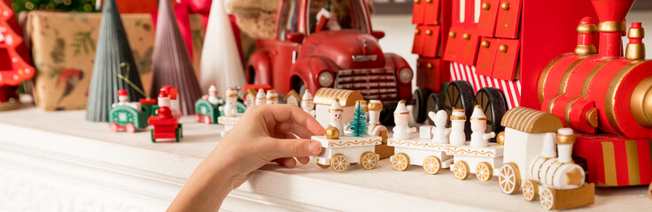 Hands of a child holding a gift, A wooden train toy is carrying New Year's gifts. Cozy home New Year atmosphere.wooden vintage train. web banner