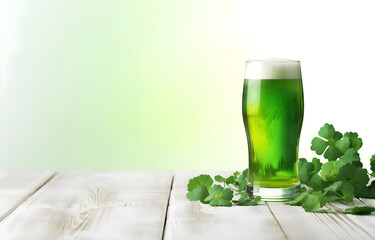 glass of green beer and clover leaf on white wooden table over white bokeh background